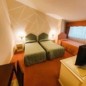 a hotel room with two beds and a television at Albergo Ristorante Bigiù in SantʼOmobono Imagna +75 photos