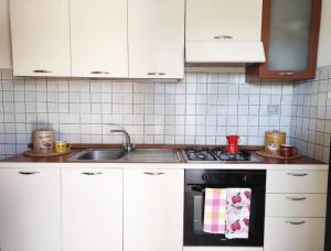 a kitchen with white cabinets and a stove top oven at Villa Smeraldo - Appartamento Fronte Mare a Capo Rizzuto in Capo Rizzuto