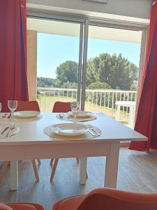 einen weißen Tisch mit Stühlen und ein großes Fenster in der Unterkunft Les Hauts de Balaruc THERMES in Balaruc-les-Bains