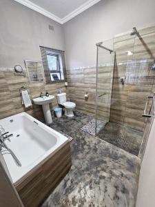 a bathroom with a tub and a toilet and a sink at Apricity Inn in Louis Trichardt