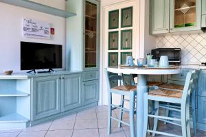 a kitchen with blue cabinets and a table with stools at Casa Acqua Marina in Castiglione della Pescaia +19 photos