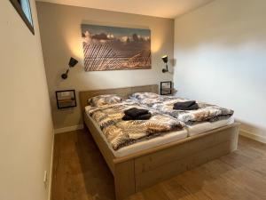 a bedroom with a bed with a painting on the wall at BeachHouse AAN ZEE in Noordwijk aan Zee