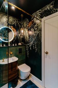 a bathroom with a toilet and a green wall at Chichester City Retreat - Stylish 4 Bed with LEGO Room, WFH Office and Free Parking in Chichester