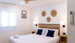 a white bedroom with two beds with blue pillows at Apartamentos Cibeles Centro Histórico in Mérida