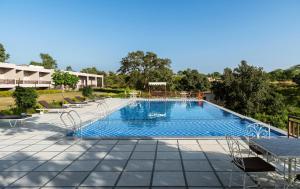 una grande piscina con sedie intorno di Kumbhal Exotica Resort Kumbhalgarh a Kumbhalgarh