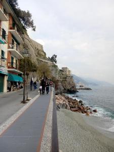 a group of people walking down a sidewalk next to the ocean at Da Cate in Monterosso al Mare