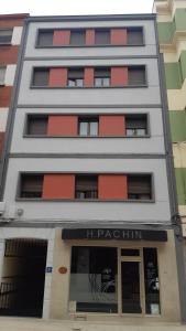 a white building with red windows and a store at Hostal pachin in Mieres