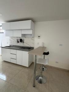 eine Küche mit weißen Schränken und einem Holztisch in der Unterkunft El refugio in Pereira