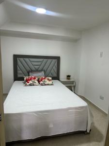 ein Schlafzimmer mit einem großen weißen Bett mit zwei Kissen in der Unterkunft El refugio in Pereira