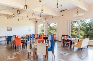 una sala da pranzo con tavoli e sedie e grandi finestre di Kumbhal Exotica Resort Kumbhalgarh a Kumbhalgarh