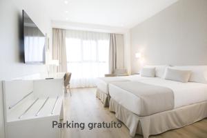 a hotel room with two beds and a desk at Hotel Albufera in Alfafar