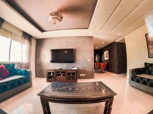 Una sala de estar con un televisor y una mesa. en Luxury and Comfort-Chic Apartment, en Agadir