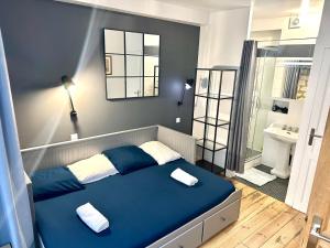 een slaapkamer met een blauw bed en een badkamer bij HSH - LE CHAPELAIS CLICHY MONTMARTe in Parijs