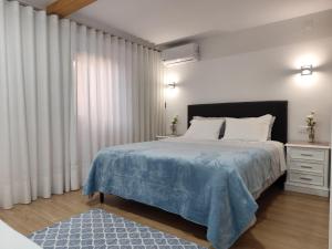 a bedroom with a large bed with a blue blanket at CASA do AÇÔR in Aldeia das Dez