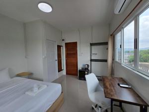 a bedroom with a bed and a desk and a table at The White Residence in Chanthaburi