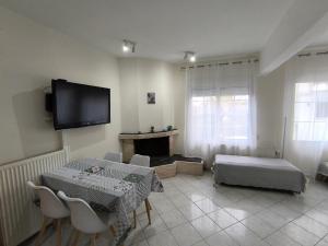 a living room with a table and a tv on the wall at Cozy Houses One in Kavala