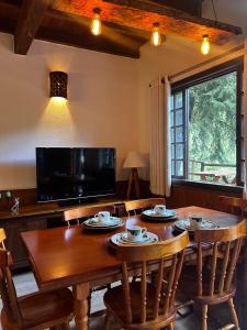 a dining room with a table with chairs and a tv at Chalé Aspen - Elegância com Vista para as Montanhas in Nova Friburgo