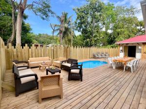 a wooden deck with furniture and a swimming pool at Bungalow cosy à Deshaies avec piscine in Deshaies