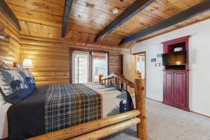 una camera da letto in stile baita di tronchi con letto e TV di Aim True North a McCall