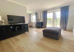 ネスマージールにあるNessmersiel, Renovierte Erdgeschosswohnung mit Garten, in Deichnähe, Wallbox,のリビングルーム(薄型テレビ、オットマン付)