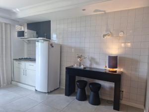 a kitchen with a refrigerator and a table with stools at Mediterrâneo flat 1309 in Rio de Janeiro