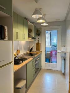 a kitchen with green cabinets and a white refrigerator at Arty Apartment - La Torre Golf Resort in Torre-Pacheco