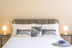a white bed with pillows and a hat on it at L'Arancio e i Pesci Rossi in Calatabiano