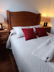 a bedroom with a white bed with red and white pillows at Casa Rural Gafas in El Toboso +63 photos