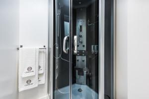 a shower with a glass door with towels in it at Lounge Inn Guest House in Porto