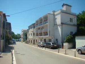 a white building on the side of a street at Apartmani sobe Matas in Kaštela