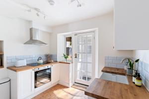 a kitchen with white cabinets and a wooden floor at Stylish cottage with balcony near seafront in Falmouth