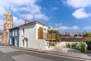 a white house on a street with a clock tower at Stylish cottage with balcony near seafront in Falmouth