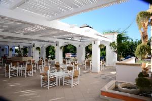 een patio met witte stoelen en tafels onder een witte pergola bij Villa Mery Villaggio Chiusurelle in Torre Lapillo