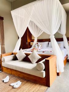 a bedroom with a canopy bed with white drapes at The Madawa Suites in Ubud