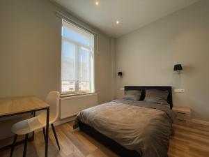 una camera da letto con un letto, una scrivania e una finestra di Midi Station a Bruxelles
