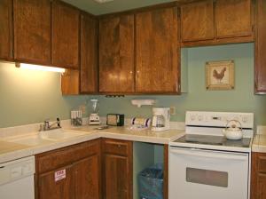 a kitchen with wooden cabinets and a white stove top oven at Bahia Vista A11 in Avalon +6 photos