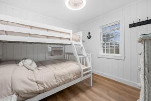 een wit stapelbed in een witte kamer met een raam bij 9 Gilbert Street South Yarmouth- No Plans in South Yarmouth