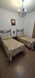 a bedroom with two beds and a chandelier at Hostal Trajano in Seville