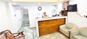 uma mulher sentada em um balcão em uma sala em Dev Hotel em Nova Deli