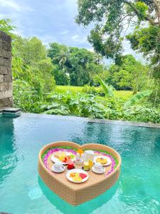 a tray of food on a table in the middle of a pool at The Madawa Suites in Ubud