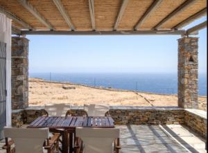 a patio with a table and chairs and the ocean at Aeraki in Kithnos