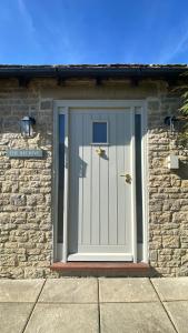 a front door of a brick building with a white door at Cosy Luxury Cotswold Retreat in Gretton