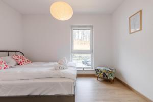a white bedroom with two beds and a window at Apartament Pod Czarnym Kotłem in Szklarska Poręba
