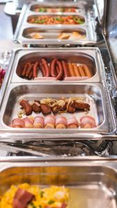 a buffet of hot dogs and other foods in trays at Moris Boutique Beach Hotel in Gdańsk