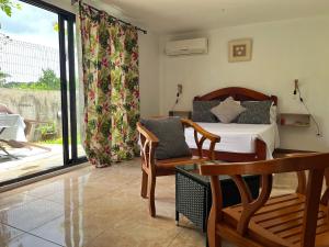 a bedroom with a bed and a chair and a window at Le mirador Chamarel in Chamarel
