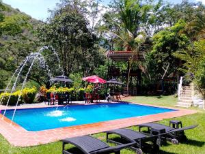 une piscine dans une cour avec une fontaine dans l'établissement Casa Verano la rumbita Naturaleza, Piscina y Rio, à Santa Fe de Antioquia 27 autres photos