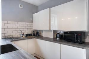a kitchen with white cabinets and a microwave at Vacant Nests The Queen Anne Central Location in Dunfermline +11 photos