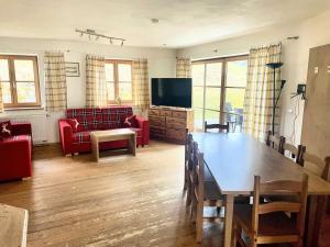 a living room with a table and a couch and a television at Landhaus Maiergschwendt inkl Chiemgaukarte in Ruhpolding