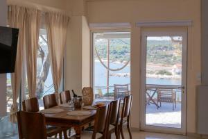 a dining room with a table and chairs and a balcony at Poseidon Apartments and Villas by the Sea in Sounio