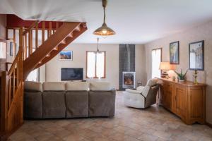 a living room with a couch and chairs and a staircase at Gîte de Caillou in Berbiguières